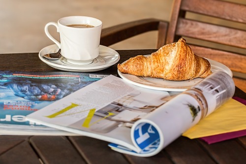 magazine, coffee, croissant on table